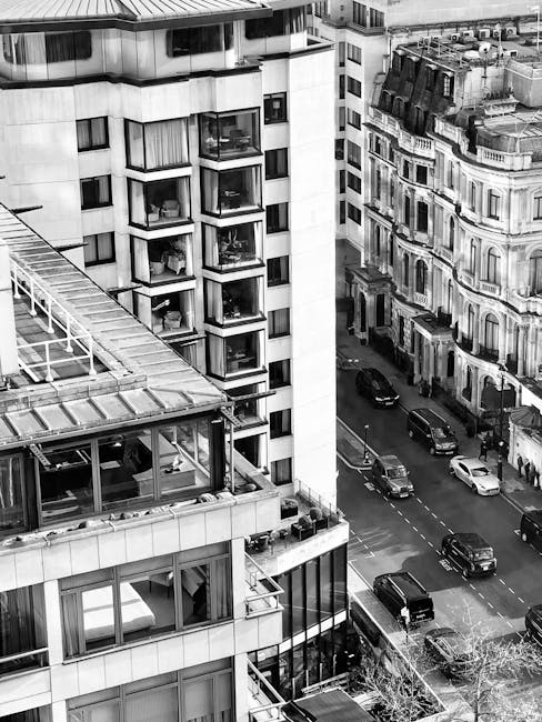 A street scene in Belgravia showing multi-story red brick residential buildings with white-framed windows and black wrought iron balconies. The buildings have rounded corners and decorative brickwork.